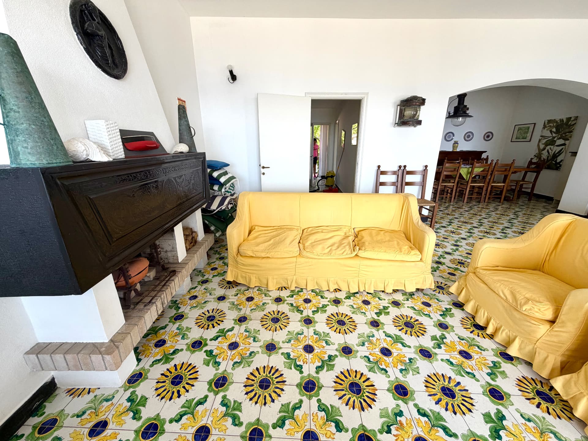 Living room with yellow sofa, fireplace and hand-painted Ligurian tiles