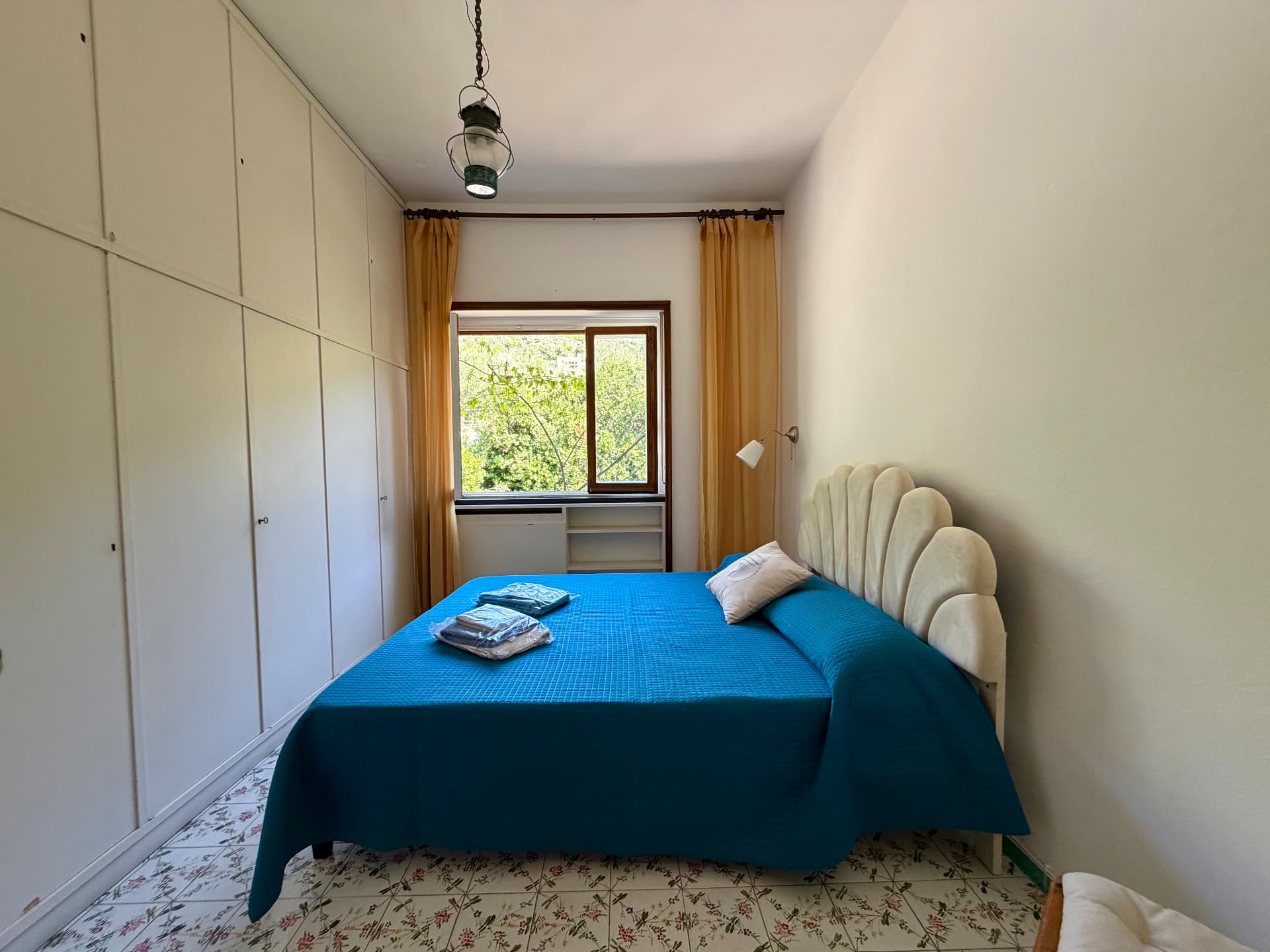 Bedroom with blue bedding and a white shell headboard