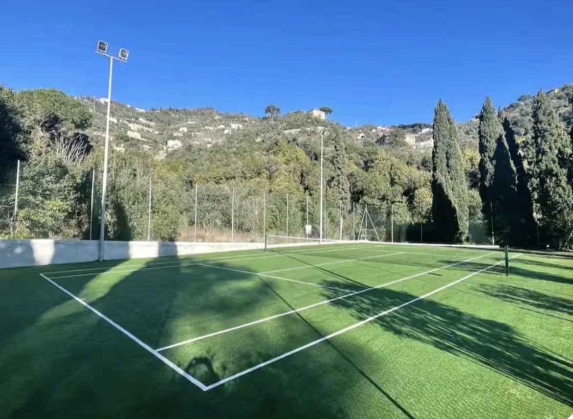 Private synthetic-turf tennis court surrounded by Ligurian hills
