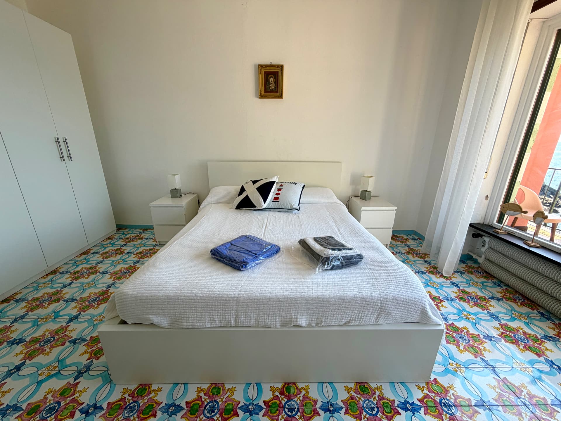 Bedroom with white linens opening onto the sea-view balcony