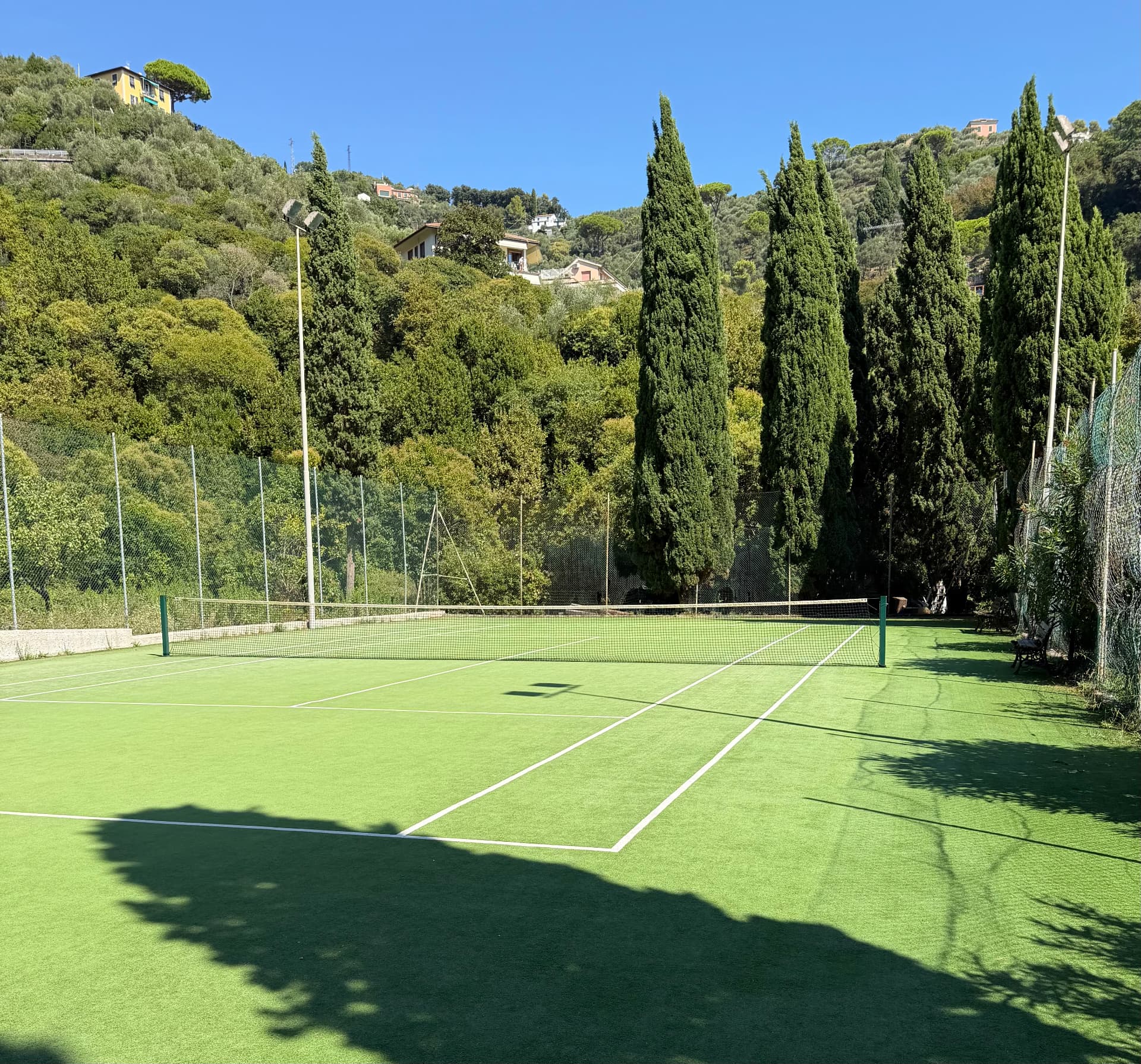 Private synthetic-turf tennis court surrounded by Ligurian hills