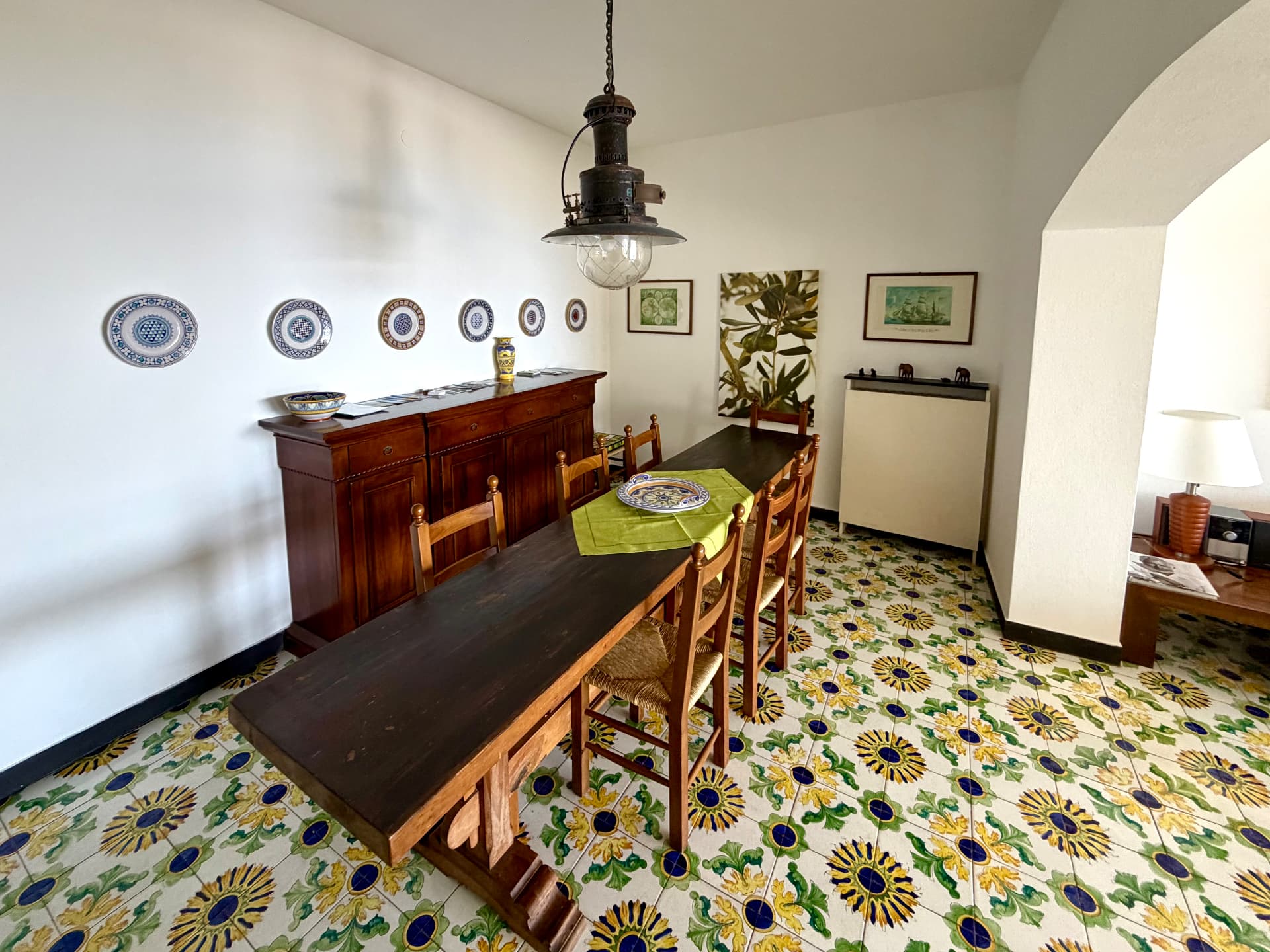 Dining room with long wooden table and patterned Ligurian floor tiles