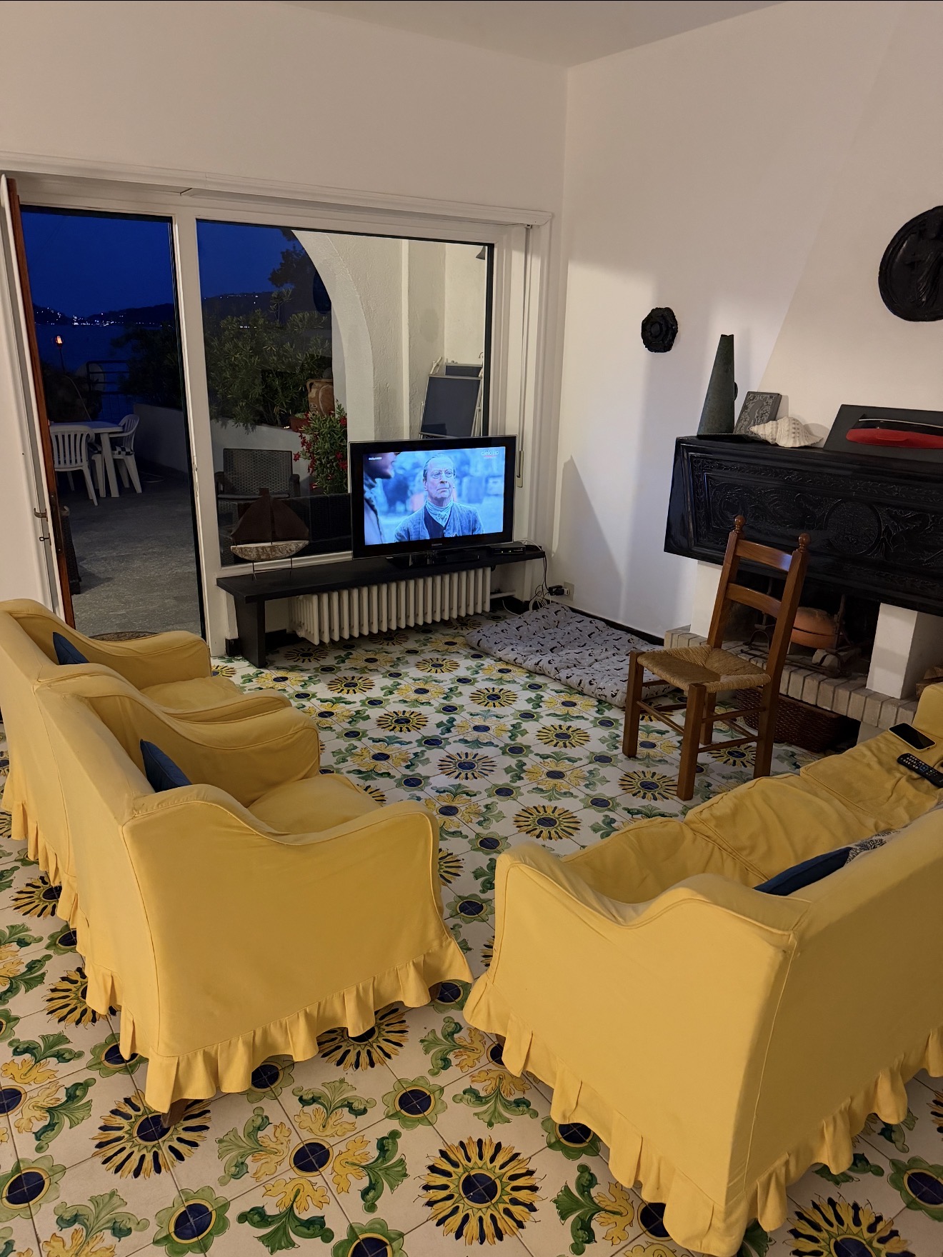 Living room with yellow armchairs, fireplace and hand-painted Ligurian tiles
